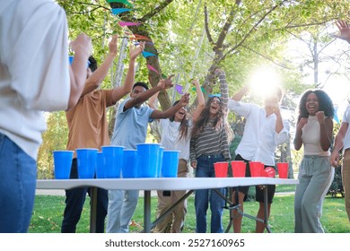 Group of friends is having a party in the park and celebrating winning a beer pong game - Powered by Shutterstock