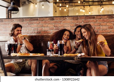 Group Of Friends Having Pizza At Cafe. Cheerful Young People Eating Pizza And Enjoying At A Fast Food Restaurant.