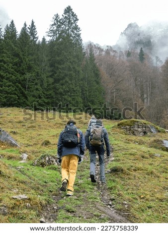 Group of friends hiking in the mountains with their backpacks on a cloudy day.Go up the mountain on a cold day and fog. They are repaired with waterproof clothing and mountain shoes. Environment humid