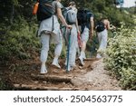 Group of friends hiking on a forest trail, enjoying outdoor adventure and bonding. They are equipped with backpacks and walking sticks.