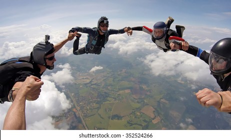 A Group Of Friends Holding Hands Teamwork In Skydiving, Soft Focus On The Clouds