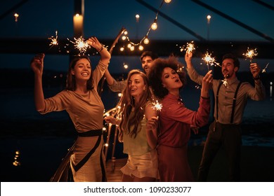 Group of friends holding sprinklers on a boat cruise - Powered by Shutterstock