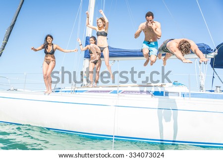 Group of friends jumping from the boat. having fun on the yacht and in the water. hot summer day and private boat party