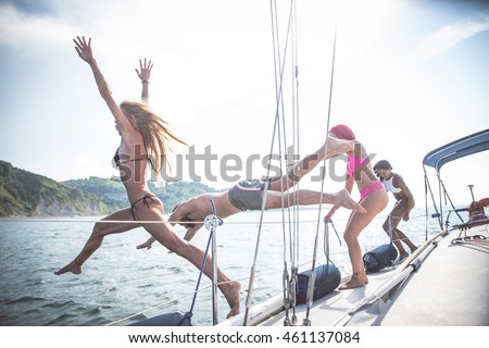 Group of friends jumping off the boat in to the sea - Young people having fun on a excursion on a sailing boat