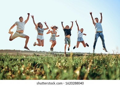 Group of friends jumping in the park on sky background. Summer, holidays, vacation, happy people concept. Bottom view