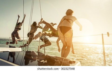 Group Of Friends Jumping In The Water From The Boat During An Excursion. Concept About Vacations,leisure And Fun