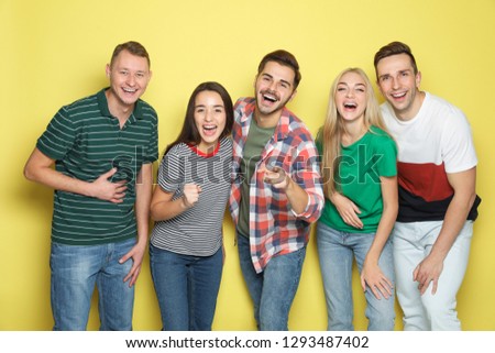 Group of friends laughing together against color background