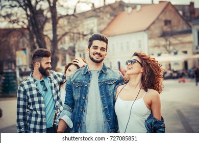 Group of friends laughing and walking at the city downtown.They embrace each other and smiling.