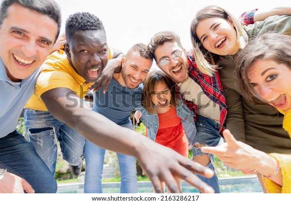 Group of friends looking camera while joking in\
big villa with pool an garden -  Funny people mixed age range enjoy\
in the vacation