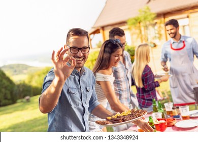 Group Of Friends Making Barbecue In The Backyard, Drinking Beer And Having Fun On A Sunny Summer Day