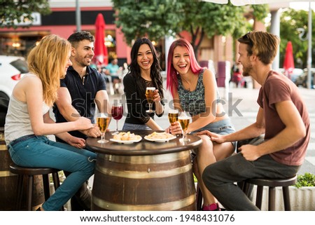Group of friends making a toast with alcoholic drinks in bar terrace
