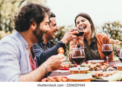 A group of friends meet on the weekend eating grilled meat, laughing, talking carefree and drinking red wine while having fun together - food and drink, leisure, people lifestyle concept - Powered by Shutterstock