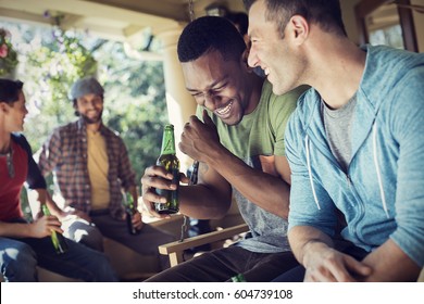 A Group Of Friends, Men And Women At A House Party Two Men Laughing