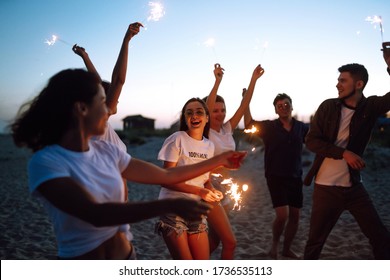 Group of friends at night on the beach with sparklers. Young friends enjoying on beach holiday. Summer holidays, vacation, relax and lifestyle concept. - Powered by Shutterstock