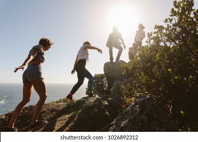 Group Of Friends On A Mountain. Young People On Mountain Hike On A Summer Day. Men And Women Climbing Rocks.