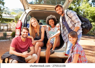 Group Of Friends On Trip Sitting In Trunk Of Car