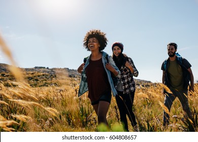 Group Of Friends On Walk Through Countryside Together. Happy Young Men And Women Hiking Together On A Summer Day.