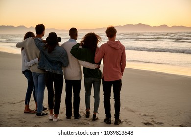 Group Of Friends On Winter Beach Watching Sunrise Together