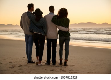 Group Of Friends On Winter Beach Watching Sunrise Together