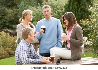 Group Of Friends Outdoors Enjoying Drink In Pub Garden