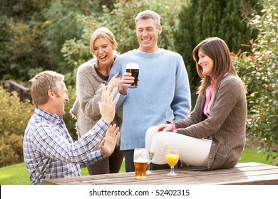 Group Of Friends Outdoors Enjoying Drink In Pub Garden