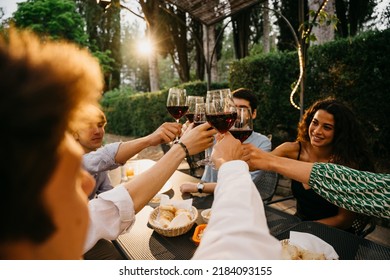 Group Of Friends Outside Eat And Have Fun Together Toasting With Red Wine Glasses At Sunset At The Hotel Restaurant Where Are Staying - Cheerful People Laugh And Joke Evening  - Party At Home