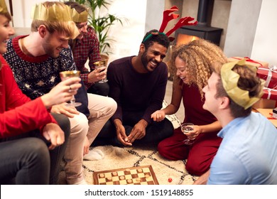 Group Of Friends Playing Board Games After Enjoying Christmas Dinner At Home