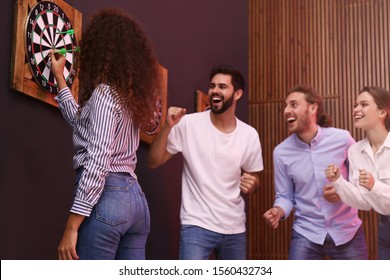 Group Of Friends Playing Darts In Bar