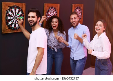 Group Of Friends Playing Darts In Bar