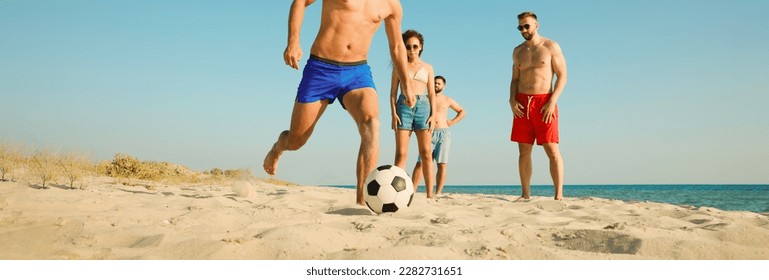 Group of friends playing football on sandy beach, low angle view. Banner design - Powered by Shutterstock