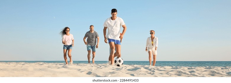 Group of friends playing football on sandy beach, low angle view. Banner design - Powered by Shutterstock