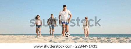 Group of friends playing football on sandy beach, low angle view. Banner design