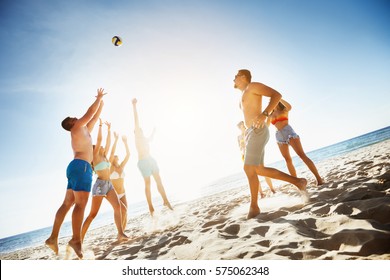 Group Of Friends Playing Game With Ball At The Beach On Background Of Sunset Sea