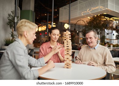 Group of friends playing in Jenga together at the table during their meeting in coffee shop - Powered by Shutterstock