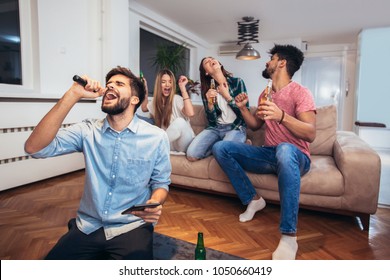 Group of friends playing karaoke at home. Concept about friendship, home entertainment and people