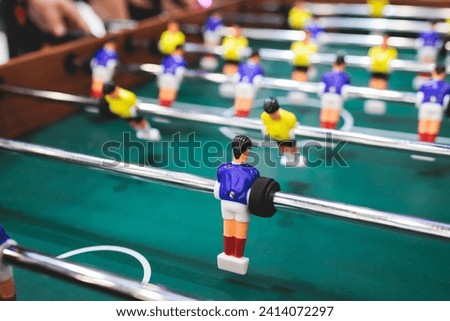 Group of friends playing kicker in a sports bar room, colleagues teammates play table football, table soccer game in the office, having fun, tabletop football match competition at work 