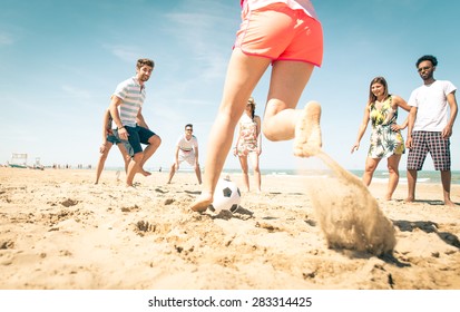 group of friends playing soccer on the beach. a girl is shooting to score a goal. concept about friends, sport, vacations and people