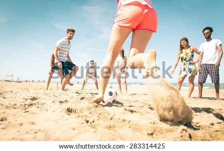 group of friends playing soccer on the beach. a girl is shooting to score a goal. concept about friends, sport, vacations and people