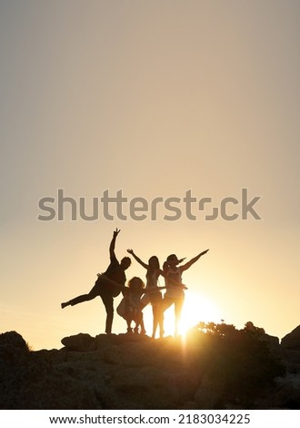 Group of friends posing standing on rocks at sunset having fun summer vacation lifestyle celebrating friendship