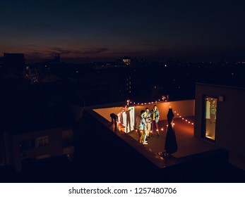 Group Of Friends Preparing For A Movie Night On The Rooftop. Aerial Shot. High Angle.
