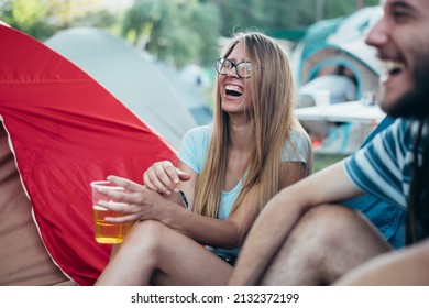 Group of friends relaxing and having fun outside tents while at the music festival. Young and cheerful couple on a music festival. Focus on the girl. - Powered by Shutterstock