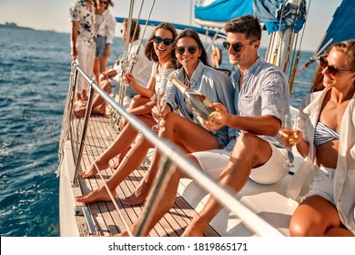 Group of friends relaxing on luxury yacht and drinking champagne. Having fun together while sailing in the sea. Traveling and yachting concept.