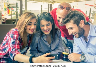 Group Of Friends At Restaurant Looking At Phone