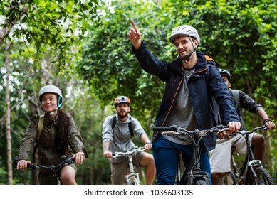 Group Of Friends Ride Mountain Bike In The Forest Together