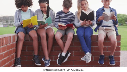 Group of friends sitting on brick wall, reading books together. African American girl, Caucasian and Biracial boys are enjoying their colorful books in casual clothes - Powered by Shutterstock