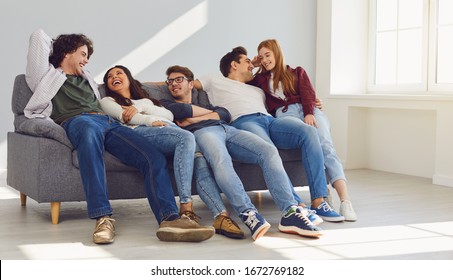 A group of friends is sitting on couch in a room on a gray background.