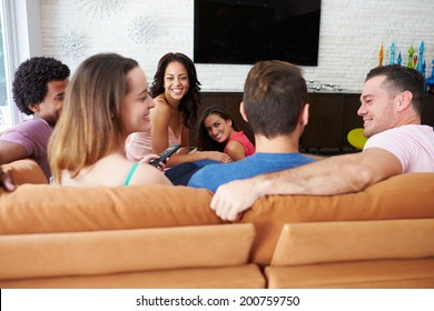 Group Of Friends Sitting On Sofa Watching TV Together