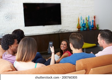 Group Of Friends Sitting On Sofa Watching TV Together