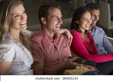 Group Of Friends Sitting On Sofa Watching TV Together