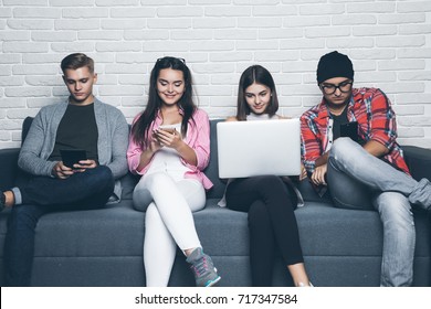 Group of friends sitting on sofa and using their gadget ignoring each other.